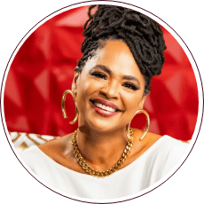 A person with dark braided hair styled upward is smiling, embodying the spirited energy reminiscent of the Fred Gray Institute. They are wearing a white top, large gold hoop earrings, and a gold chain necklace. The red background features a decorative pattern that echoes the fight for civil rights.